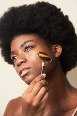 Beautiful African American woman using a Tiger's Eye Precious Stone Facial Massager in a skincare routine