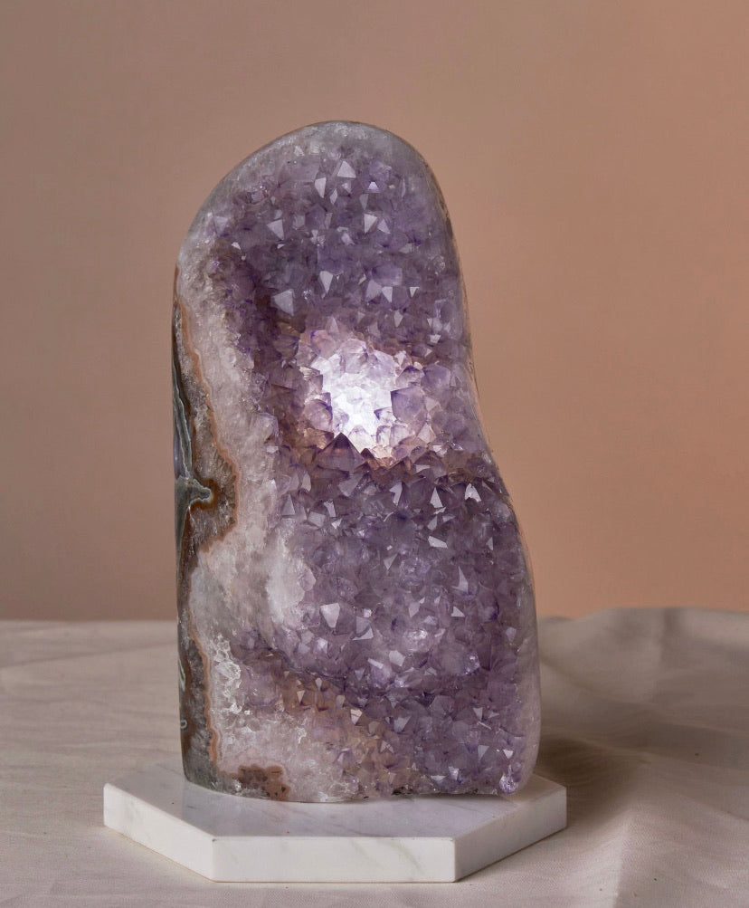 Enhance your space with Amethyst lamps known for tranquility, clarity, and spiritual growth. Stylish decor suitable for all ages. Radiate healing and protective energy with their soft glow. Each set includes a polished amethyst lamp and electric tealight bulb. Available in sizes: Medium (4-6”), Large (7-10”), XL (8-14”). Please note natural size variations.