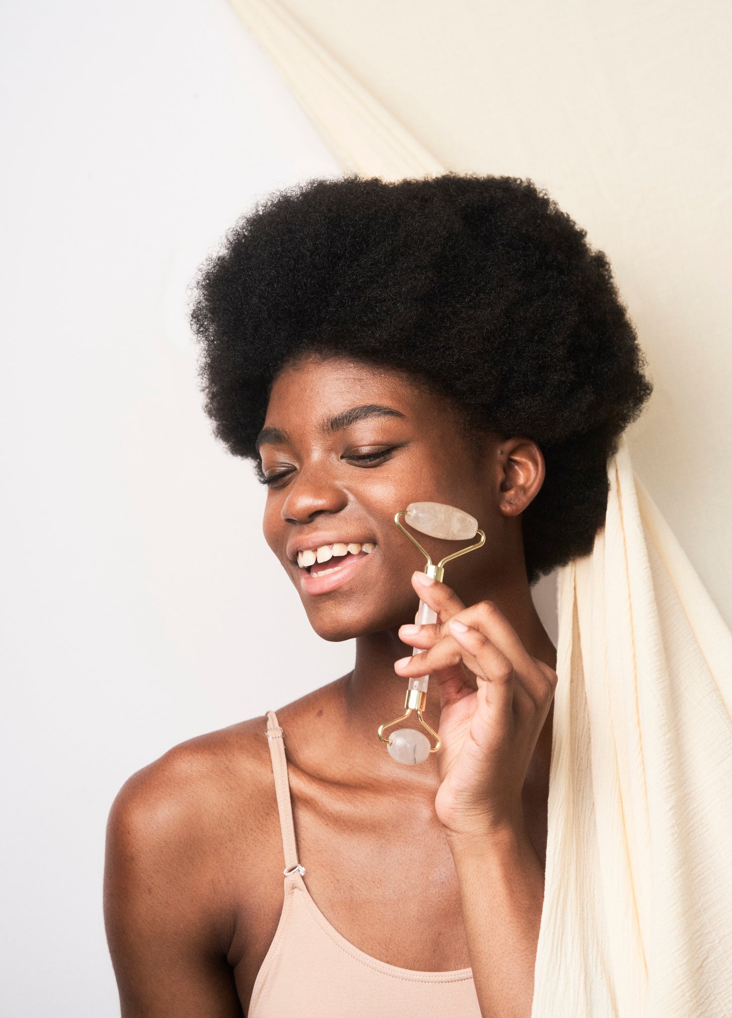African American woman using a Rose Quartz Precious Stone Facial Massager for radiant and refreshed skin.
